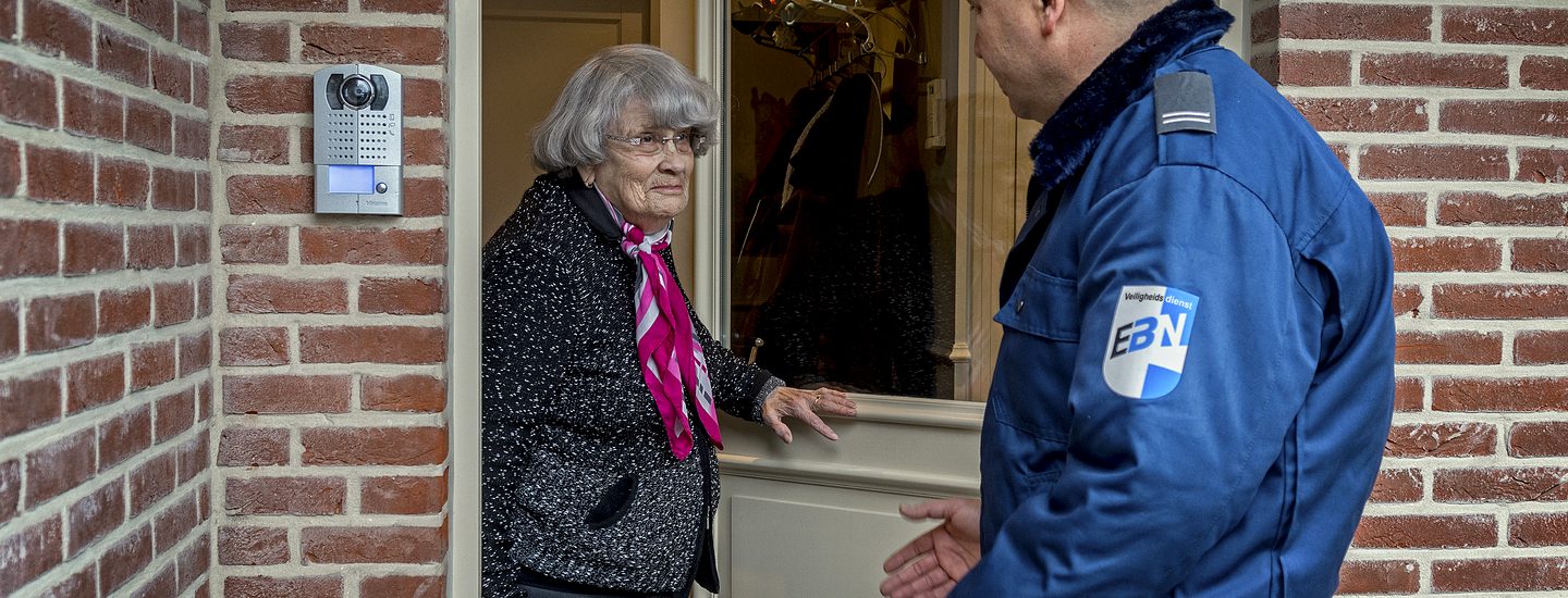 EBN beveiliger in gesprek met bewoonster aan de voordeur met intercom